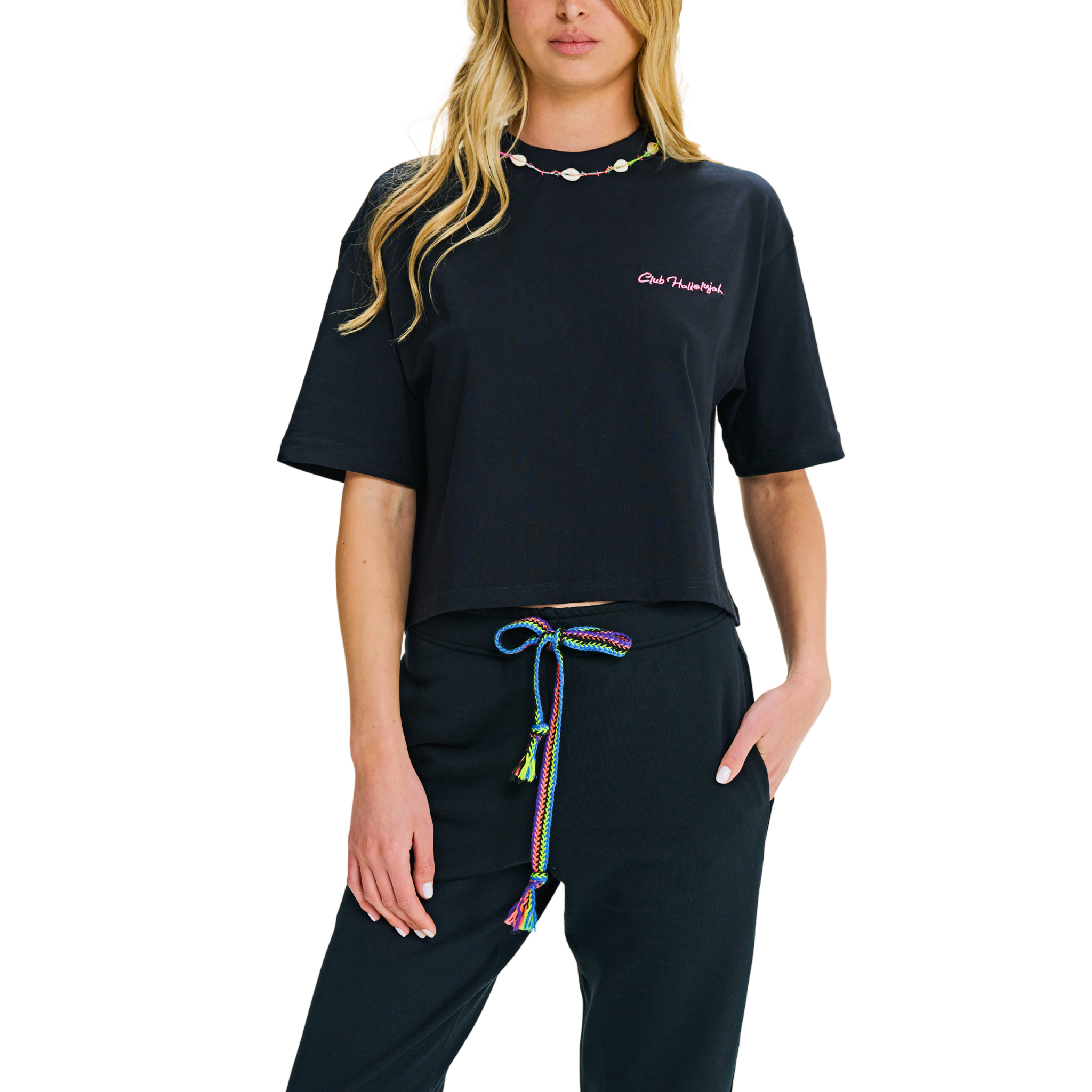 Model in black crop top, side-front view, showing pink embroidery and cowrie shell neckline