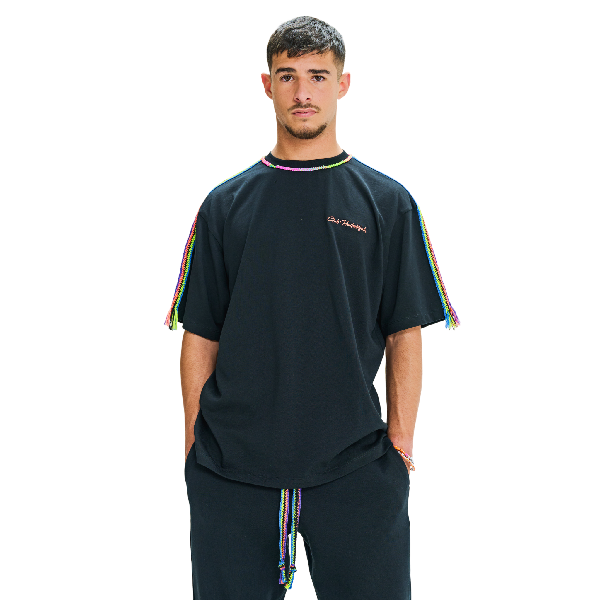 Front view of male model in black oversized T-shirt with embroidered chest logo and handmade braided multicolor shoulders