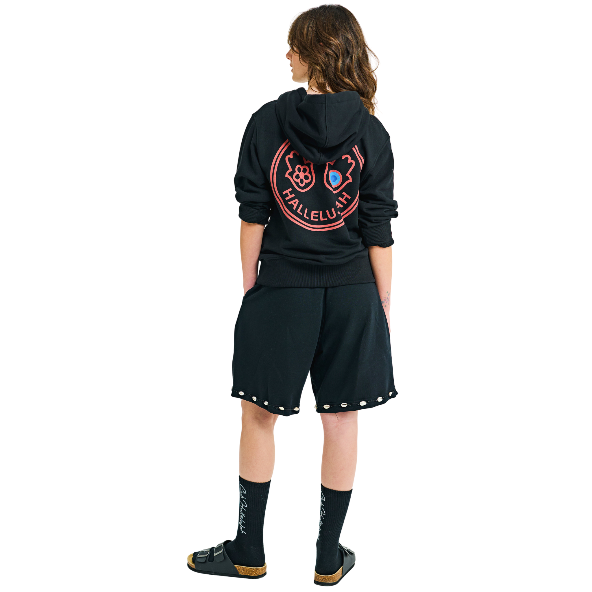 Back view of female model in unisex black shorts, braided drawstring, cowrie shell hem, graphic Club Hallelujah print on back
