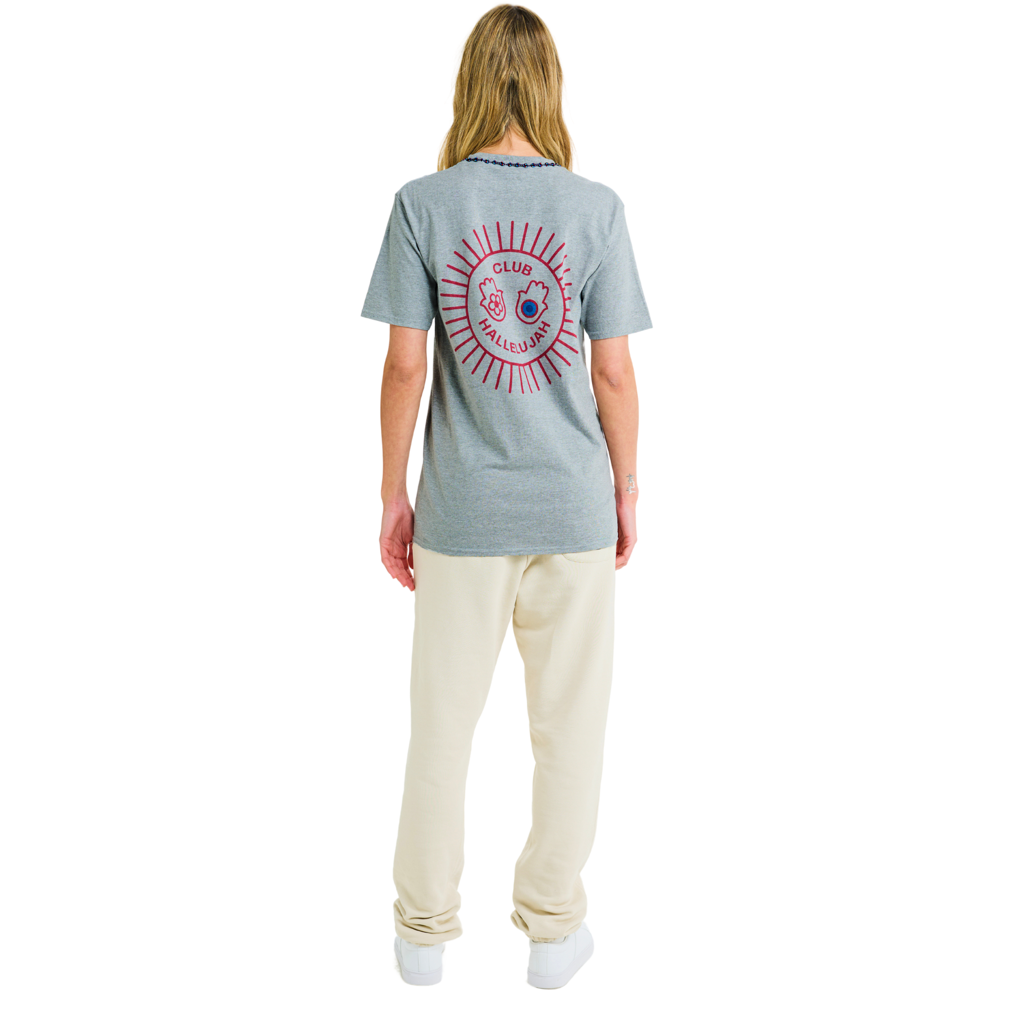 Female model wearing ash grey mélange T-shirt, back view, showing red sunburst print and braided neckline