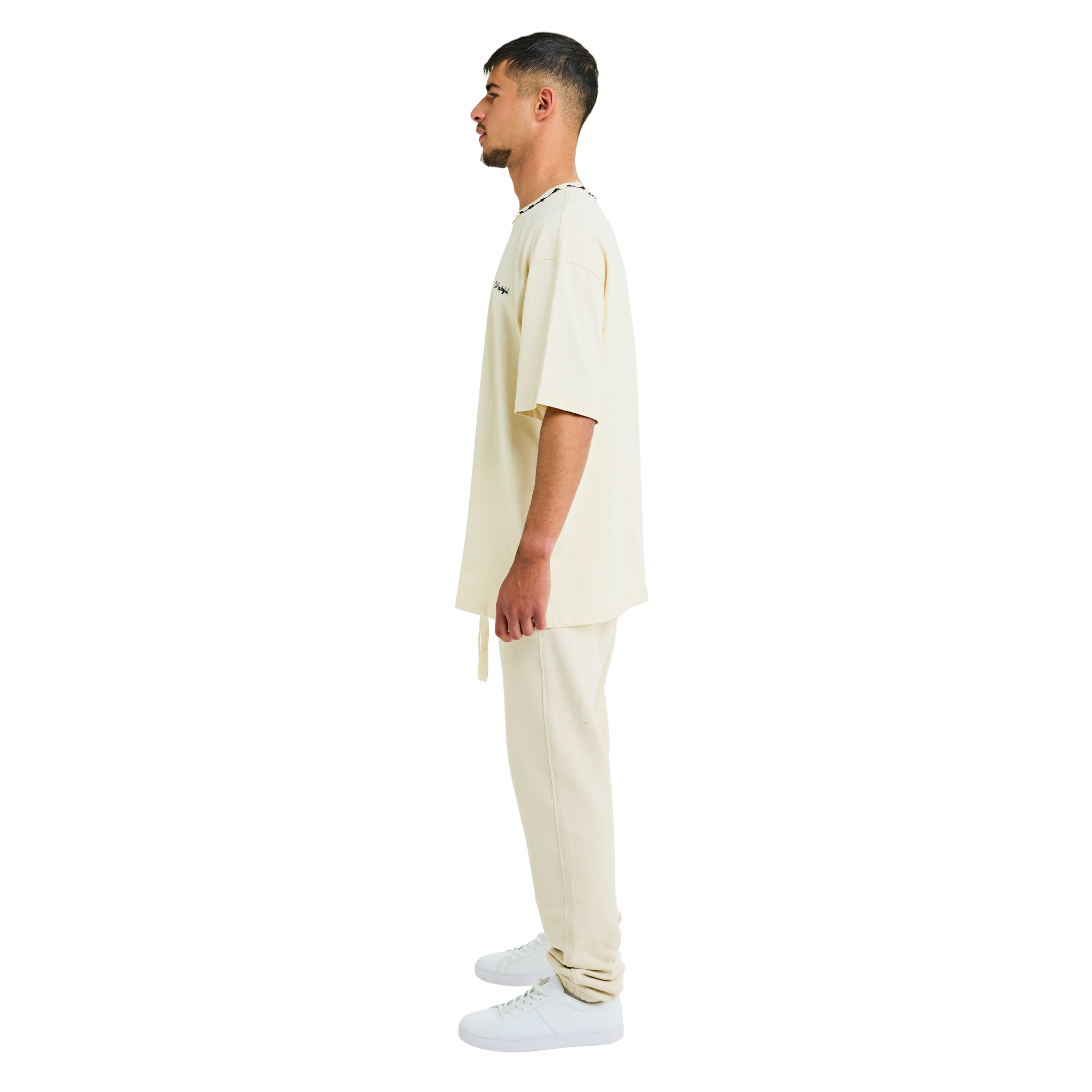 Side view of male model in unisex sabbia oversized T-shirt with embroidered chest logo and handmade braided neckline
