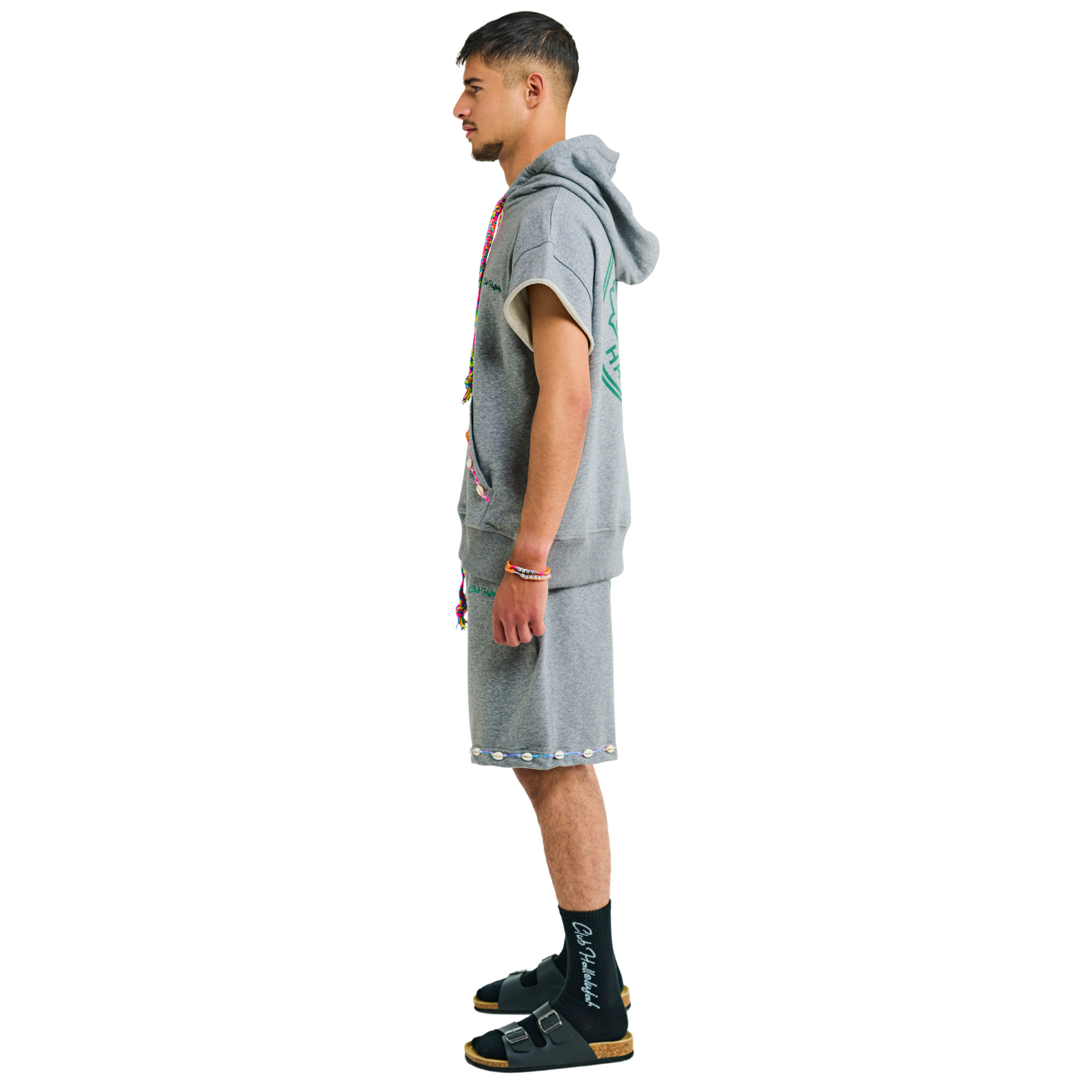 Side view of male model in unisex gray melange short-sleeved hoodie, 100% cotton, handmade cowrie shells, multicolor drawstring, Club Hallelujah logo