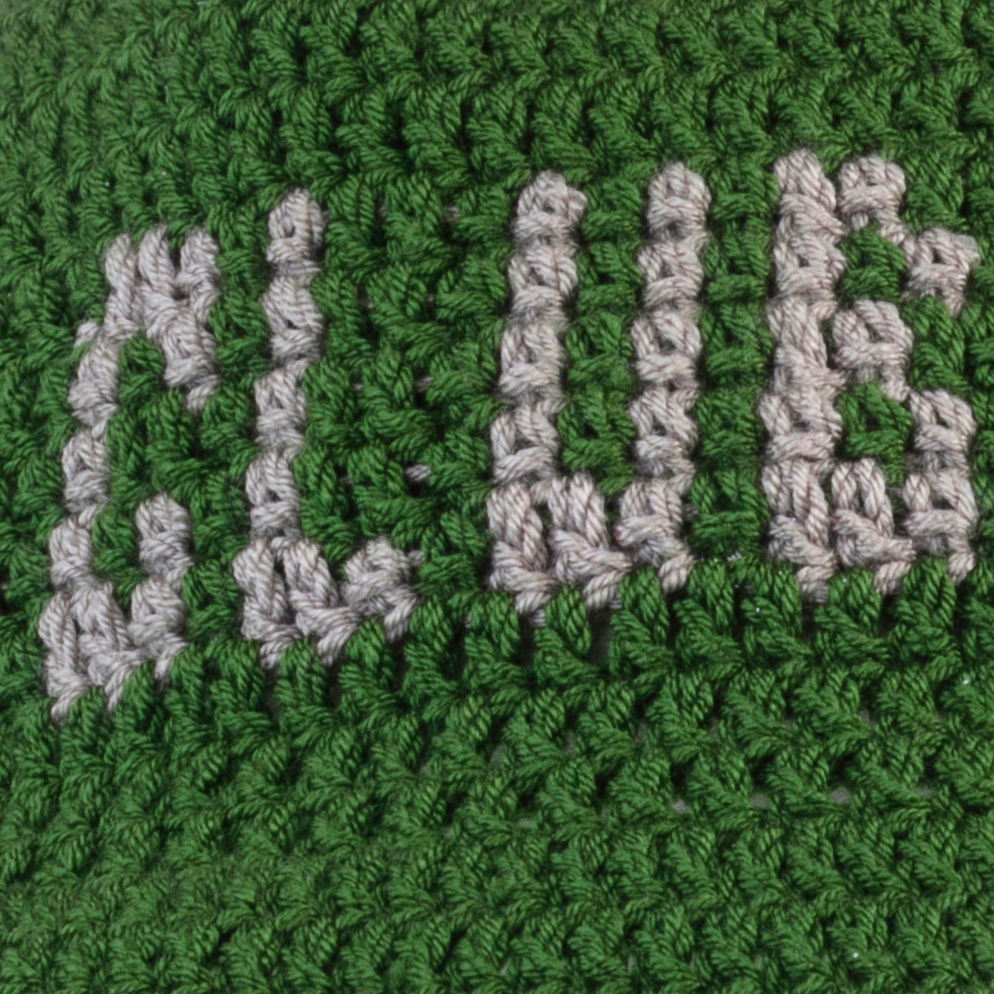 Close-up of green crochet bucket hat, showing hand-stitched 'Club Hallelujah' lettering detail