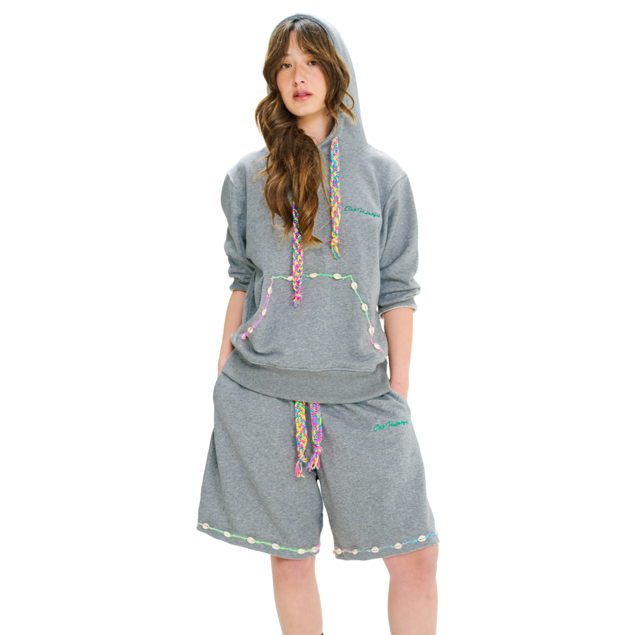 Front view of female model wearing unisex grey hoodie with kangaroo pocket, embroidered cowrie shells, and braided drawstring