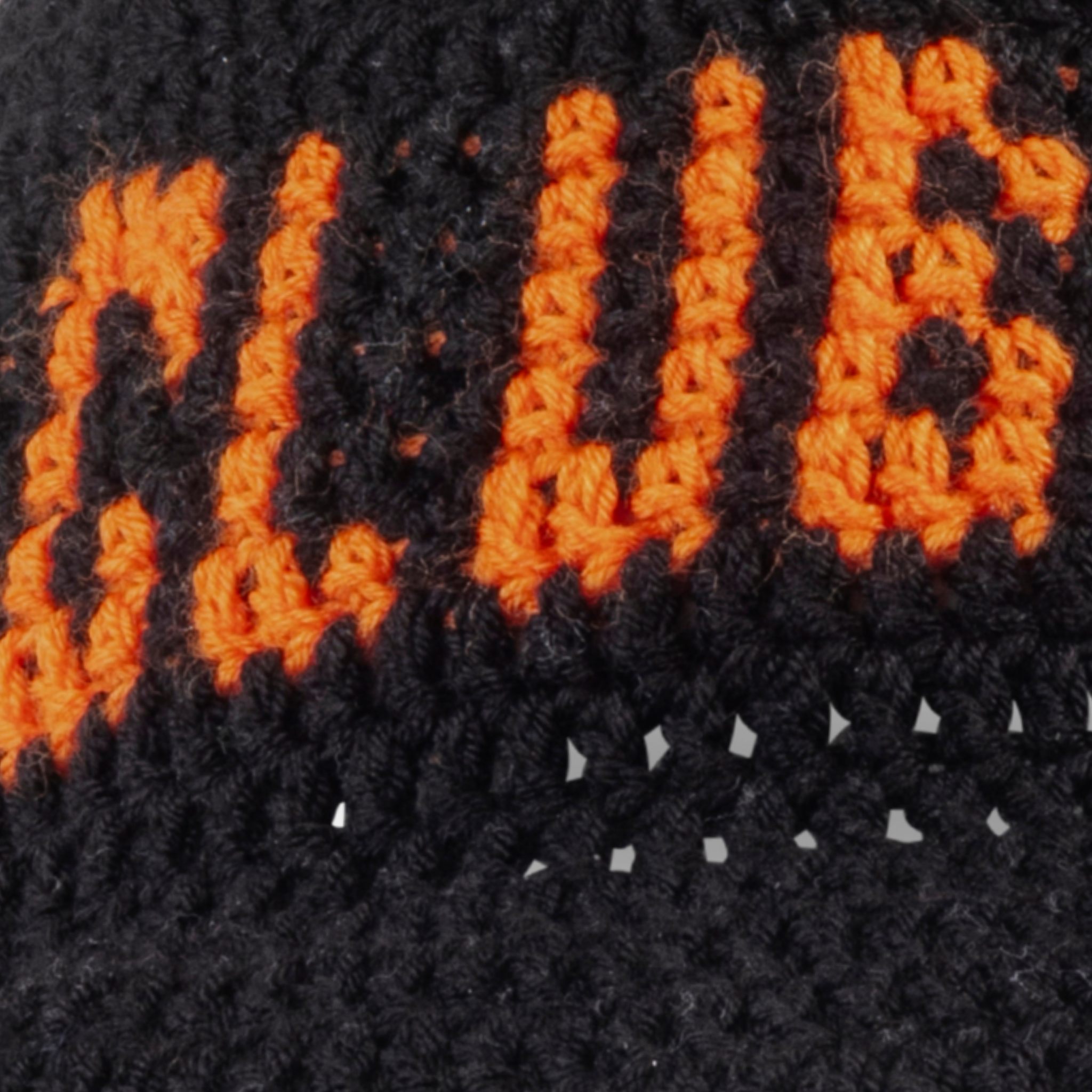 Close-up of orange 'CLUB HALLELUJAH' lettering on black hand-crocheted bucket hat