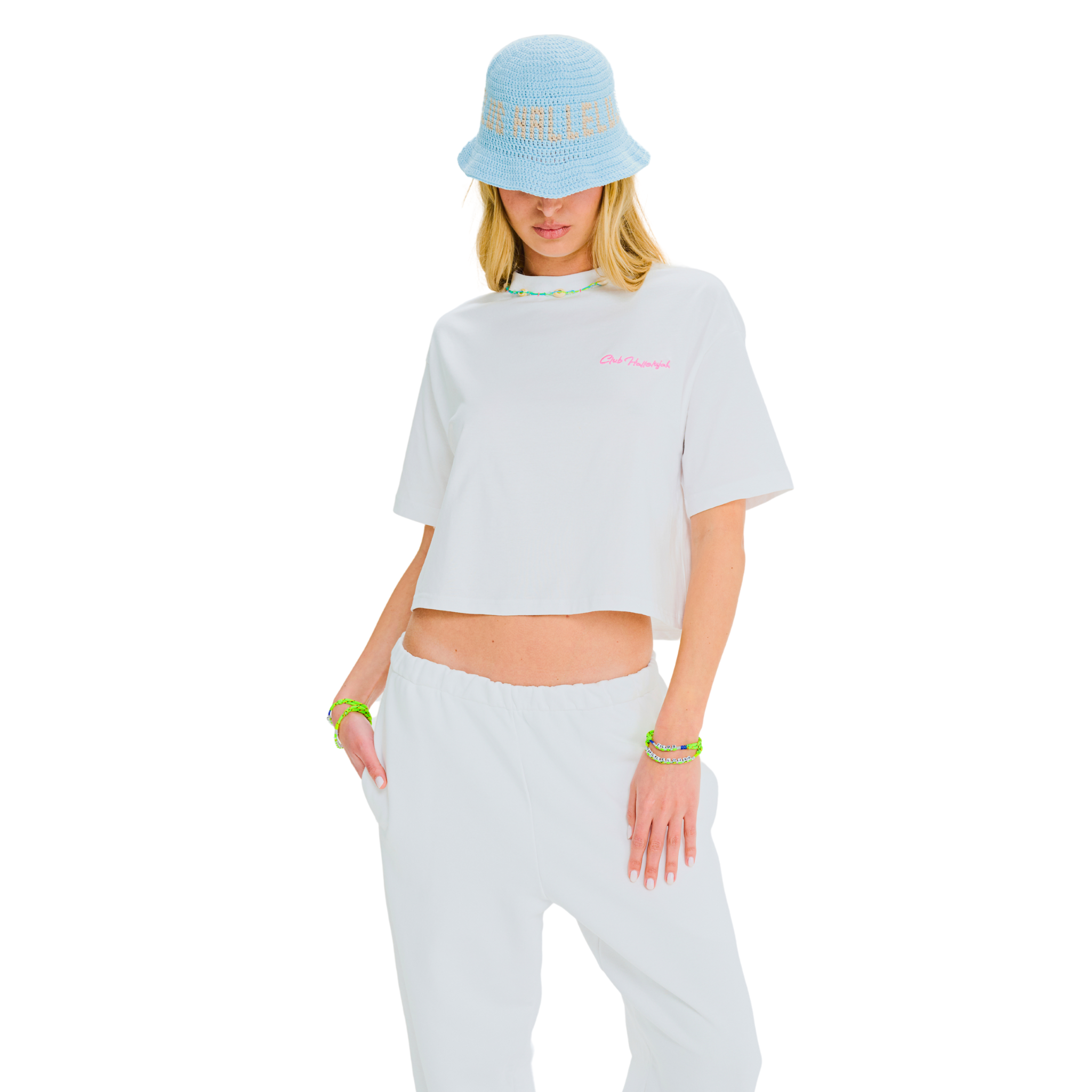 Model posing in white crop top with pink embroidery and cowrie shell neckline, side-front angle