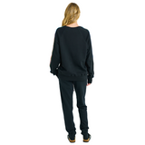 Back view of female model in black oversized raglan sweatshirt with plain back and handmade braided sleeve details