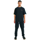 Male model front view in black oversized T-shirt with embroidered logo and braided multicolor shoulders
