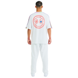Back view of male model wearing white oversized T-shirt with large printed graphic logo and braided shoulders