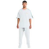 Male model front view in white oversized T-shirt with embroidered chest logo and braided handmade shoulders