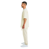 Side view of male model in unisex sabbia oversized T-shirt with embroidered chest logo and handmade braided neckline