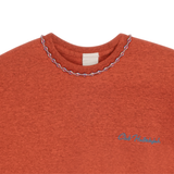 Close-up of orange mélange T-shirt neckline with handmade braided ribbon and small front logo
