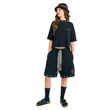 Model in black crop top, walking pose, showing front logo and back hamsa prints with braided cord