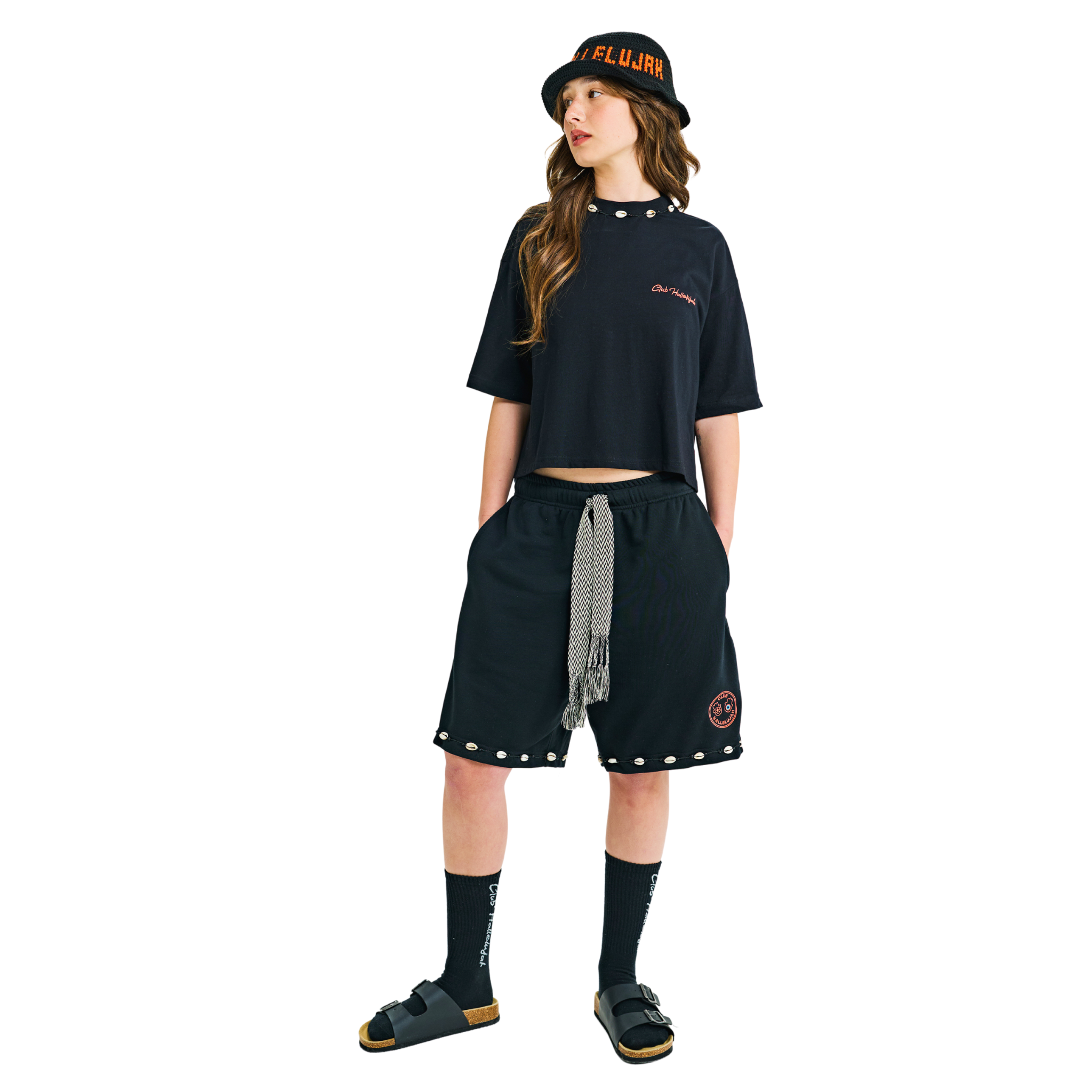 Model in black crop top, walking pose, showing front logo and back hamsa prints with braided cord