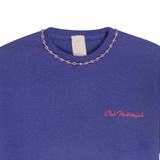 Close-up of purple mélange T-shirt neckline with handmade braided ribbon and small front logo