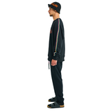 Side view of male model wearing oversized sweatshirt with hand-braided colorwork on sleeves