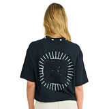 Model wearing black crop top, back view, showing sunburst appliqué and cowrie shell neckline