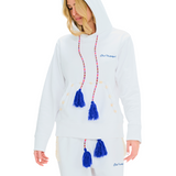Female model side view in unisex white hoodie, blue tassel drawstring, cowrie shell pocket trim, 100% cotton, handmade details