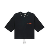 Black organic cotton crop top with pink 'Club Hallelujah' embroidery, cowrie shell neckline, and tassel detail, front view